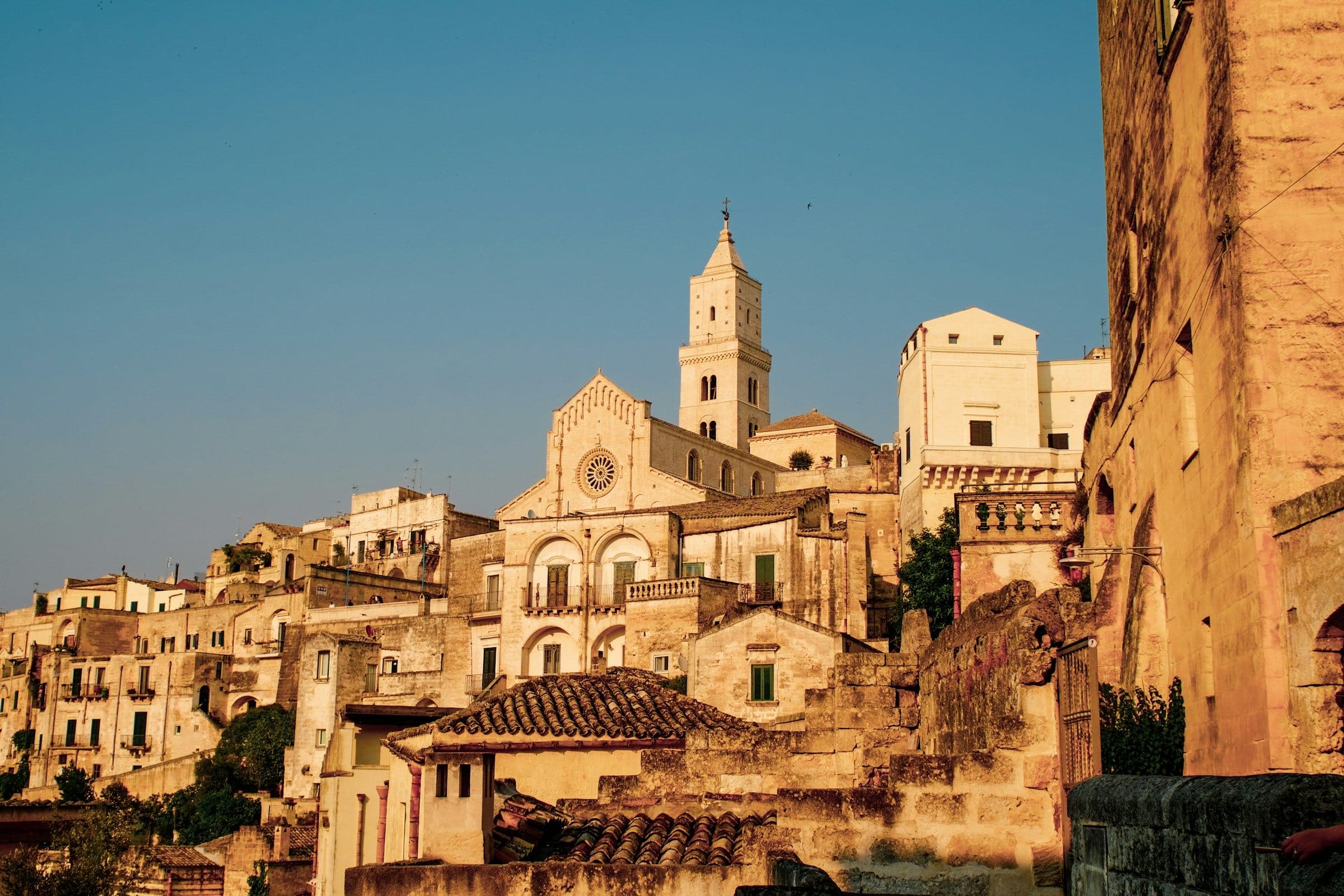 Low golden sun on Matera's carved stone and cathedral tower